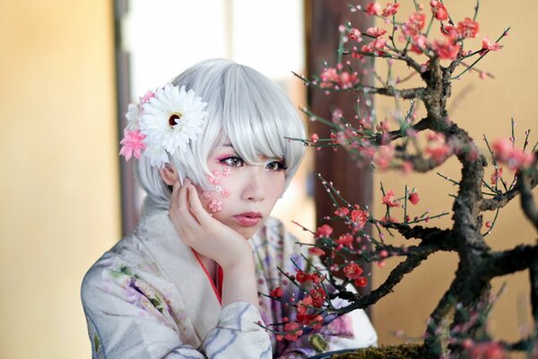 Ragazza asiatica guardando un bonsai in fiore