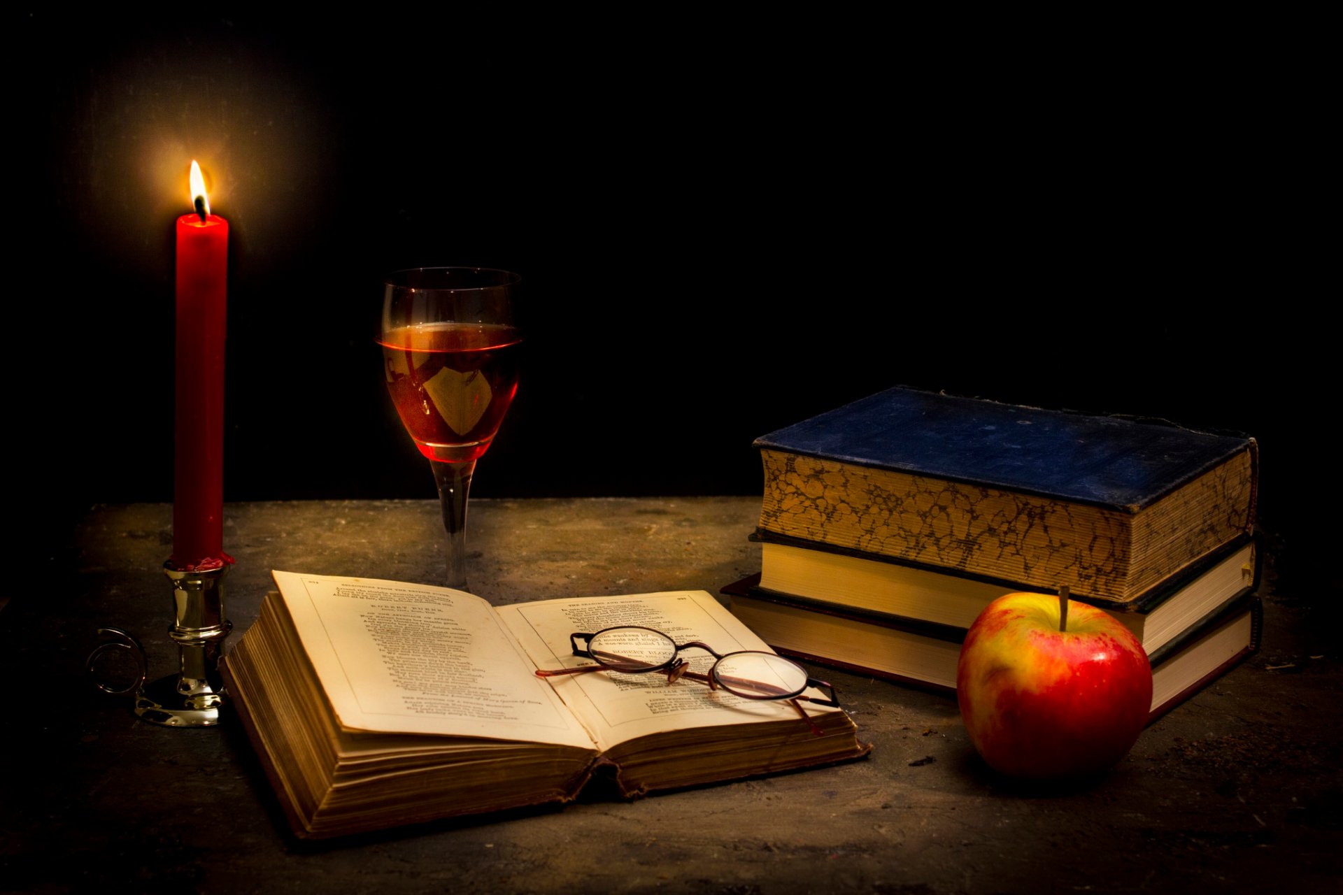 calma nel buio candela libri occhiali bicchiere di vino mela