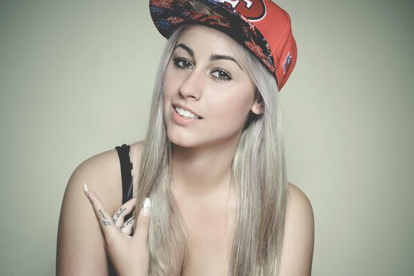 Blonde with a red cap on a gray background