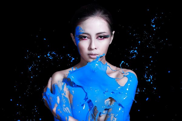 Fille en peinture bleue sur fond noir