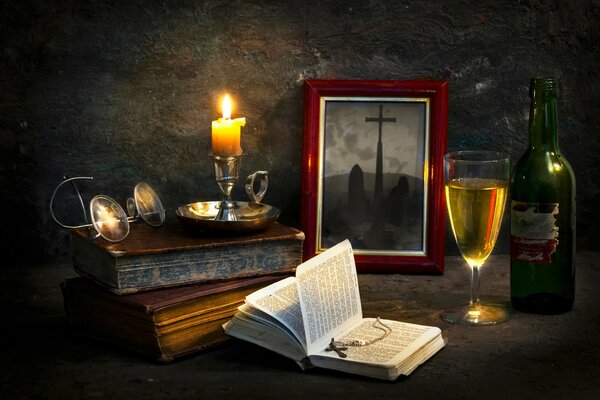 An old still life with a bible of candles and a glass of wine