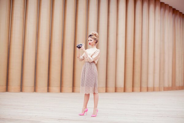 Mädchen mit einer Kamera in einem Kleid und rosa Schuhen