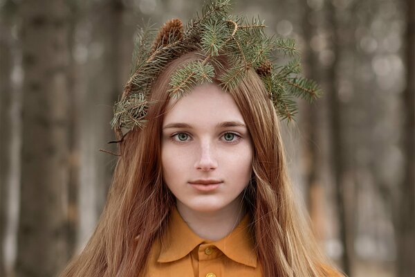 Charming red-haired girl with a wreath of cones