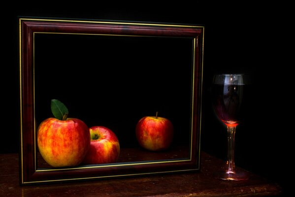 Dark still life with a frame apples and a glass of wine