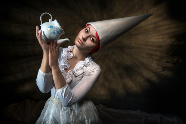 A girl in a strange hat is holding a teapot