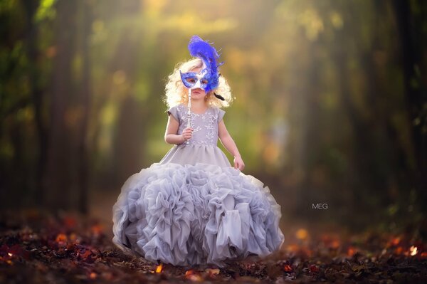 Petite fille en robe de bal avec masque bleu