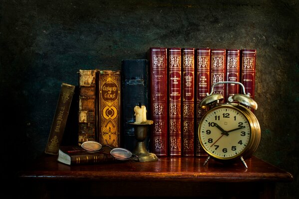 Candle and clock on the background of books