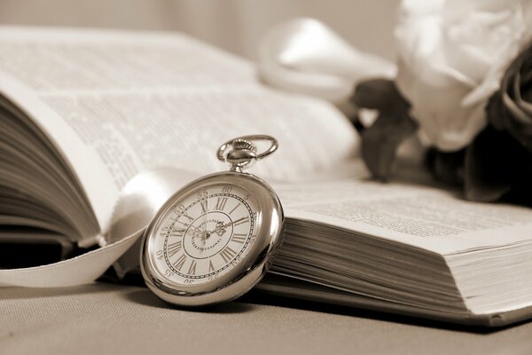 An open thick book and a small clock leaning against it