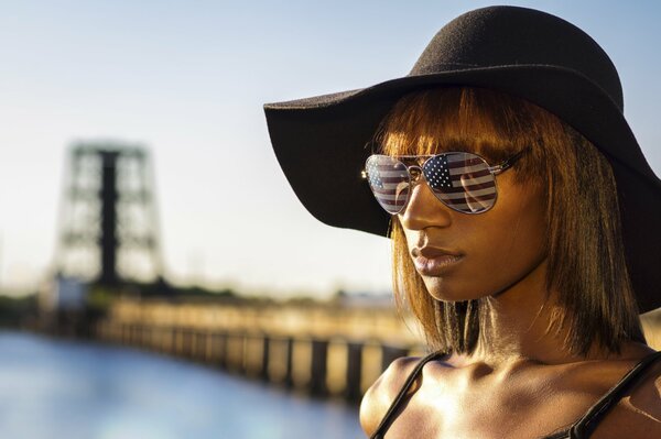 Chica con sombrero y gafas que reflejan la bandera de América