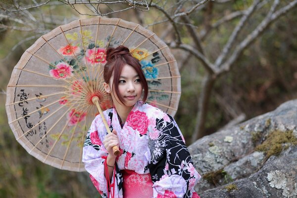 Asiatische Mädchen in einem stilvollen Outfit mit einem Regenschirm