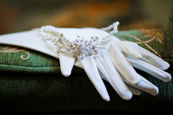 Snow-white gloves and jewelry lie on the pillow