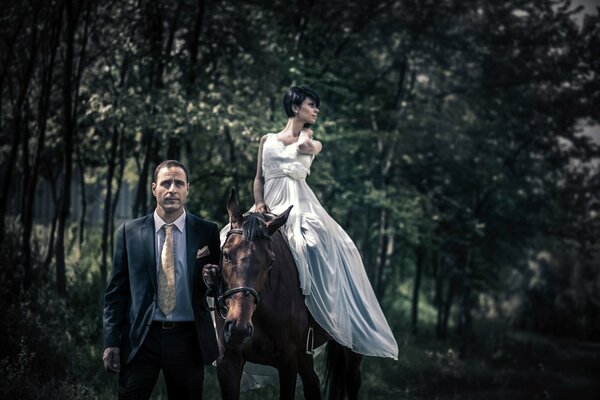 Homme en costume conduit un cheval avec une fille à cheval, couple élégant