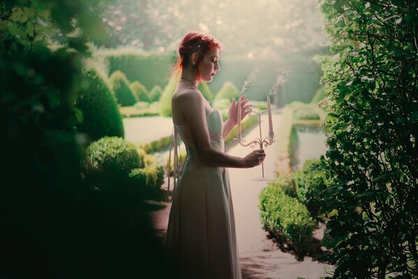 Girl in the garden in a dress with candles