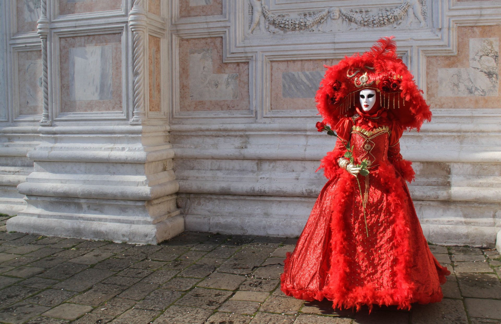 chica vestido de carnaval rojo máscara sombrero flor rosa pared