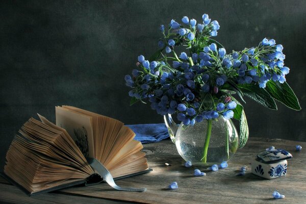 Livre ouvert sur une table à côté d un vase de fleurs