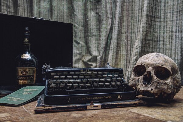 Typewriter, skull, bottle and passport on the table