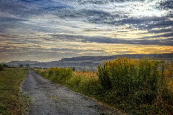 Straße in einem Feld unter Sonnenuntergang