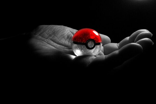 Rotes Pokéball auf der Handfläche auf schwarzem Hintergrund