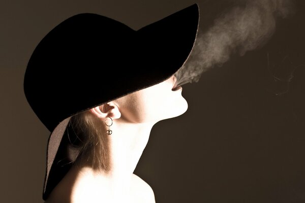 Belle fille dans un chapeau avec un cigare