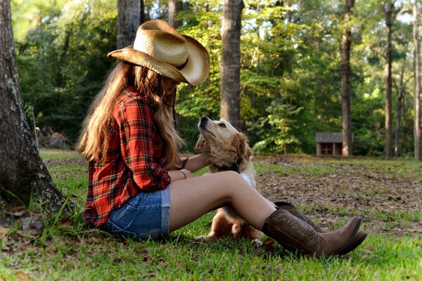 La ragazza con il cappello accarezza il cane sotto l albero