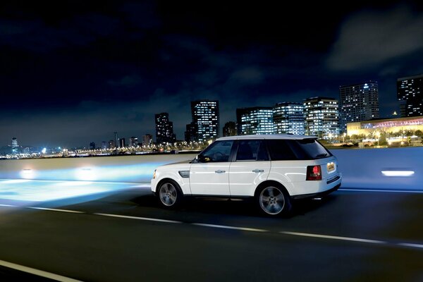 Against the background of a night city, a white jeep