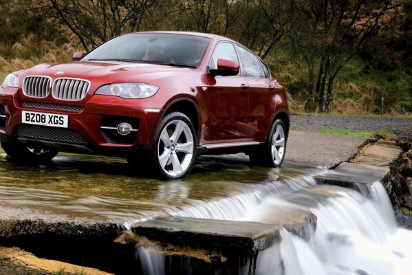 Bmw cerca de una cascada en la naturaleza junto a los árboles