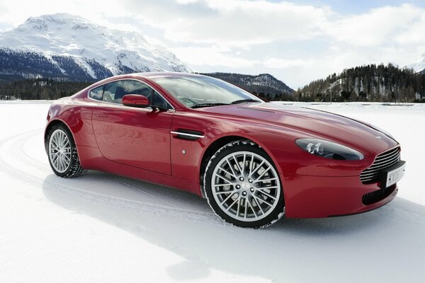 Macchina rossa sullo sfondo di montagne nella neve