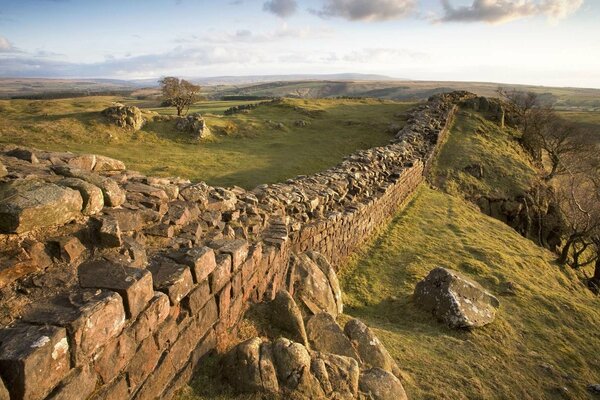 Zerstörte alte Mauer in einem Feld über einer Klippe