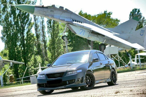 An airplane exhibit on the background of a black car driving