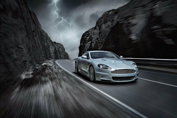 Un aston martin viaja a gran velocidad por una carretera de montaña