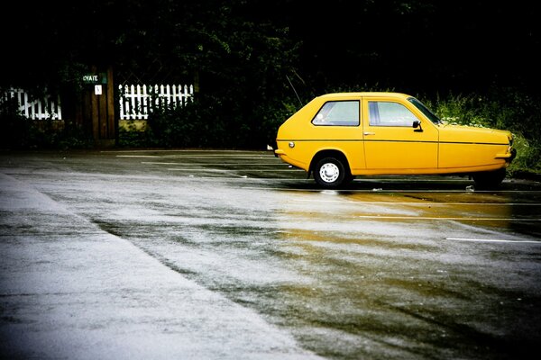 Coche amarillo parado sobre asfalto mojado