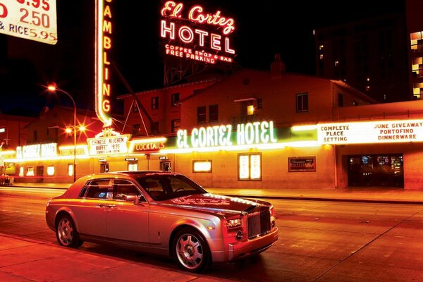 Rolls royce sur fond de publicité au néon et la ville de nuit