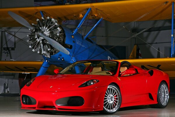 Ferari rosso in un hangar con un aereo