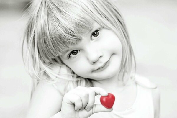 Foto en blanco y negro de una niña con un corazón rojo brillante