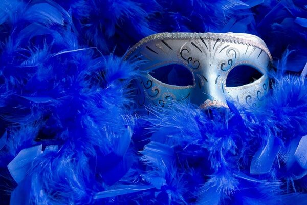 Máscara de carnaval asomándose de plumas azules