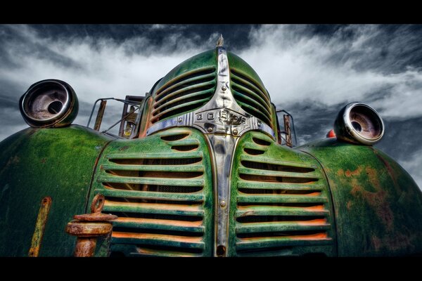 Un coche verde muerto contra un cielo nublado