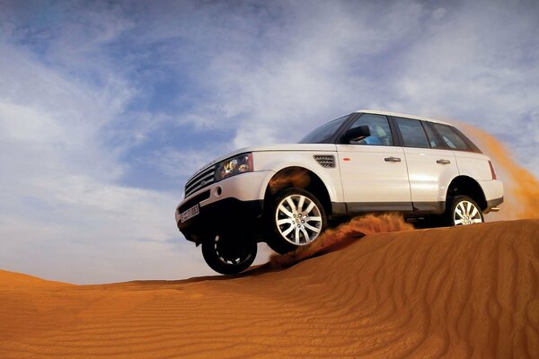 Weißer Jeep springt aus Sand über den Sand