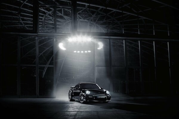 Porsche noir dans le garage avec la lumière directionnelle sur la voiture