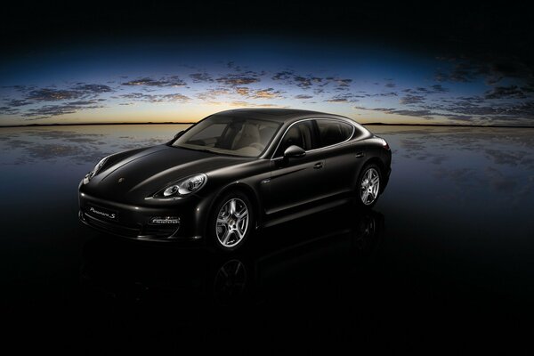 Coche Porsche negro en medio de la puesta de sol