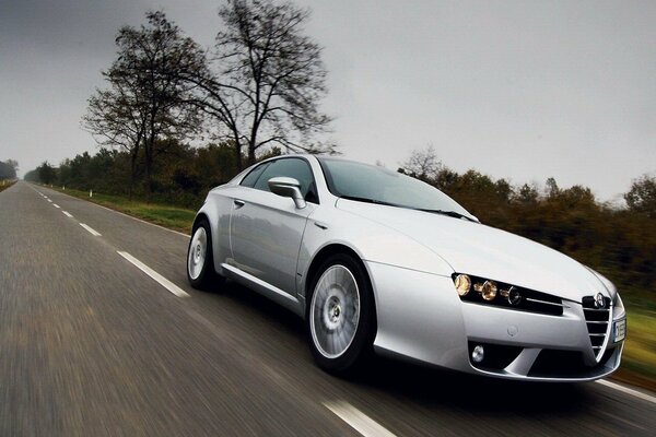 A grey car is driving on the road