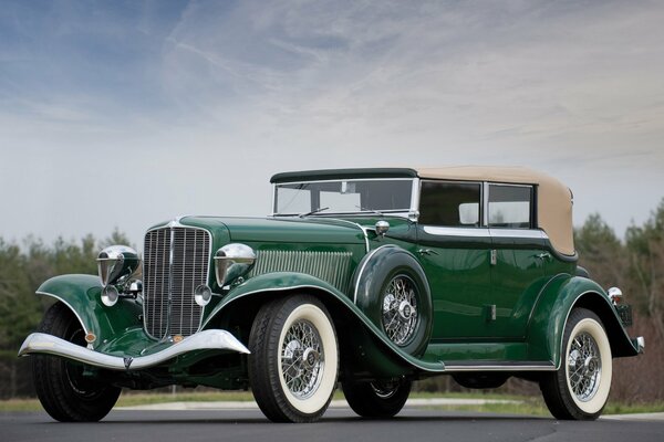 An old green car with spokes in the wheels