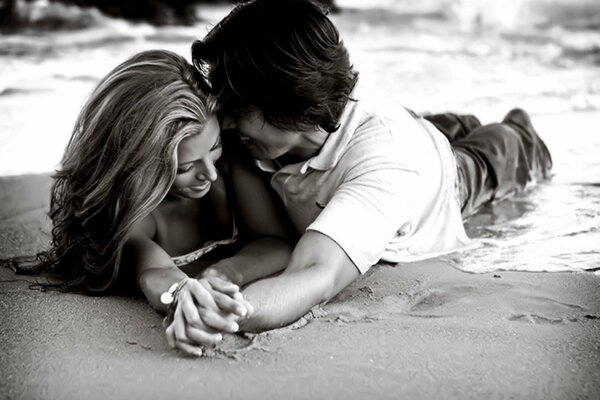 El chico y la chica yacen en la arena. Imagen en blanco y negro