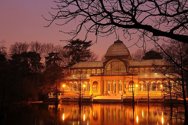 A building with bright lights and reflection in a pond