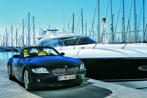 Ein BMW neben einer schicken Yacht mit einem Mann an Bord