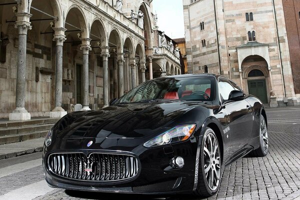 Un Maserati negro se encuentra en la carretera de la ciudad