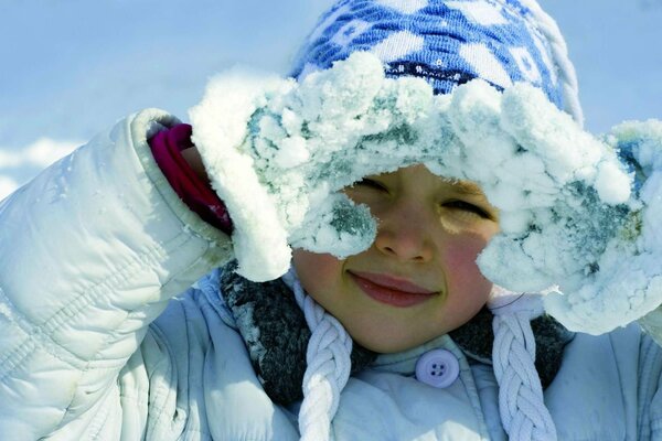 A girl poses in winter in mittens