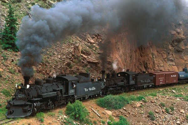 Auf dem Berg rast eine Dampflokomotive, und Rauch kommt aus dem Rohr