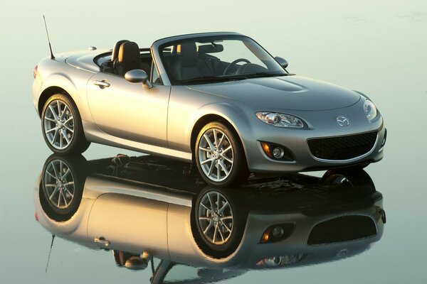 The gray Mazda on the convertible stands on a mirrored surface