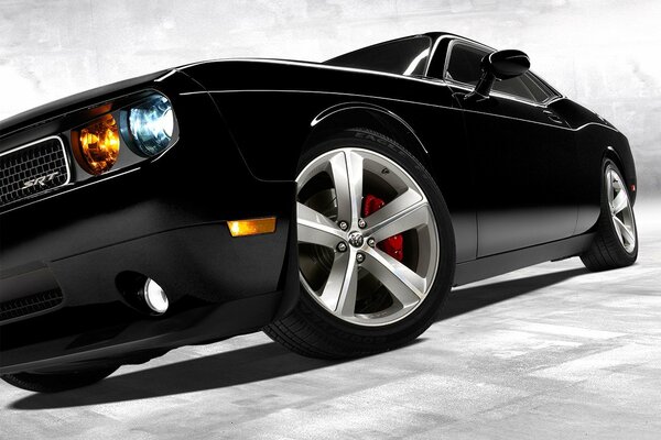 Black powerful car with headlights on and wide wheels