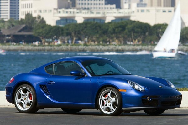 Blauer Porsche auf dem Hintergrund von Wasser und Segelboot